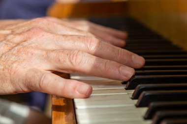 A mans hands playing a piano, with selective focus