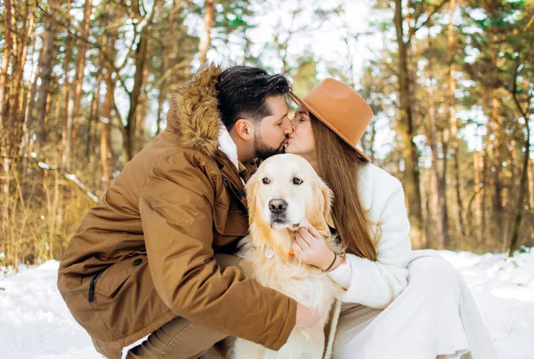Aile açık havada. Romantik bir kadın ve vahşi bir adam kış ormanında Golden Retriever köpeğiyle vakit geçiriyorlar..