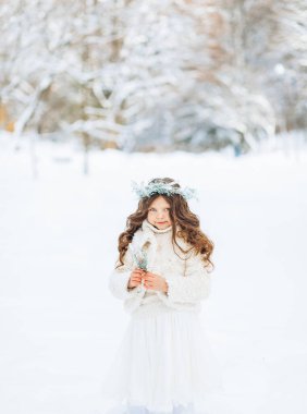 Pozitif küçük bir kız kış parkının arka planına kar kusar. Noel zamanı.