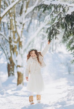 Karlı kış yürüyüşünde oynayan mutlu çocuk. Küçük kız tatilin tadını çıkarıyor. Hafif arkaplanda bir çocuğun portresi.