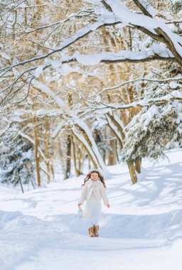 Muhteşem bir kız elinde bir fenerle orman yolunda yürüyor. Noel zamanı. Güneşli kış günü.