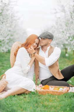 Piknik, bahar otlağında genç bir çift. Çiçek açan kiraz ağaçları sokağı.