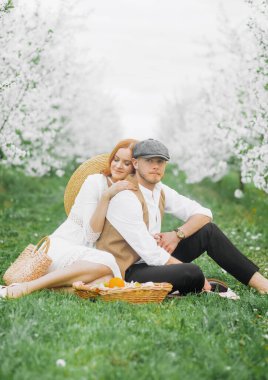 Piknik, bahar otlağında genç bir çift. Çiçek açan kiraz ağaçları sokağı.