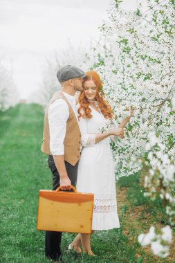 Eski tarz giyinmiş güzel bir çift çiçek açan sokakta poz veriyor..