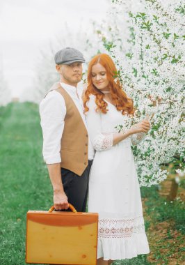 Eski tarz giyinmiş güzel bir çift çiçek açan sokakta poz veriyor..