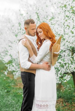 Piknik, bahar otlağında genç bir çift. Çiçek açan kiraz ağaçları sokağı.