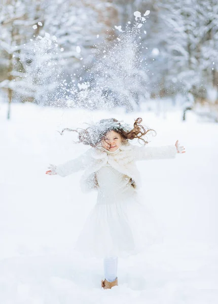 肯定的な女の子は冬の公園の背景に雪を投げます クリスマスタイム — ストック写真