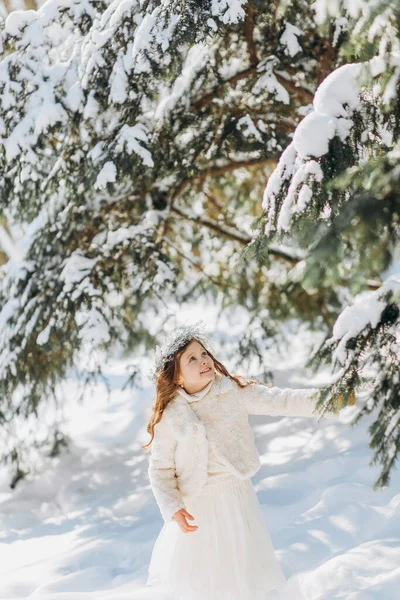 Küçük kız tarafından kar kaplı çam ağacının dalını sallayarak.