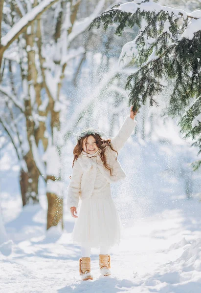 Karlı kış yürüyüşünde oynayan mutlu çocuk. Küçük kız tatilin tadını çıkarıyor. Hafif arkaplanda bir çocuğun portresi.