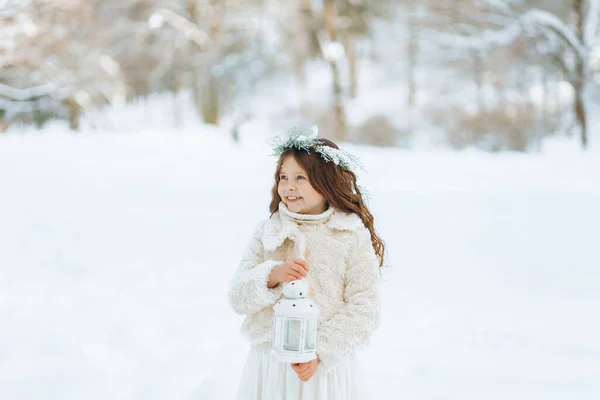 小さな女の子は雪を楽しんでいます 手にクリスマスの提灯を持った花輪の少女 クリスマスの背景 — ストック写真