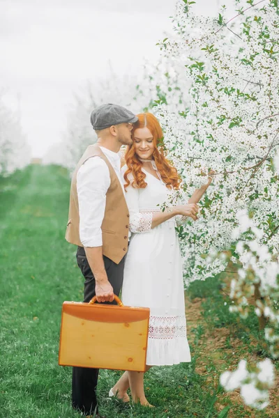 Eski tarz giyinmiş güzel bir çift çiçek açan sokakta poz veriyor..