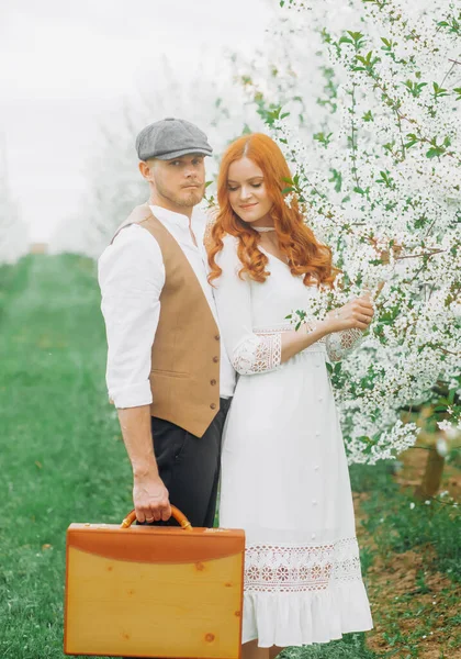 Eski tarz giyinmiş güzel bir çift çiçek açan sokakta poz veriyor..