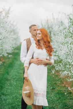 Piknik, bahar otlağında genç bir çift. Çiçek açan kiraz ağaçları sokağı.