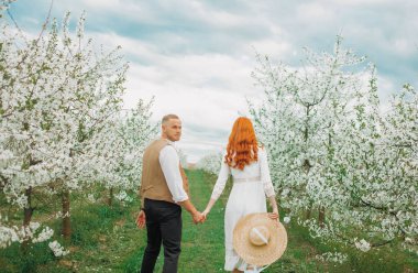 Aşık bahar çifti. Bahar Parkı 'nda yürüyen ve güzel bahar çiçeklerinin tadını çıkaran çift..