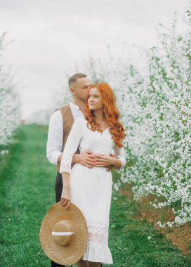 Açık havada aşık mutlu bir çift. Sevgi dolu bir adam ve kadın bahar çiçekli bir parkta yürüyorlar..