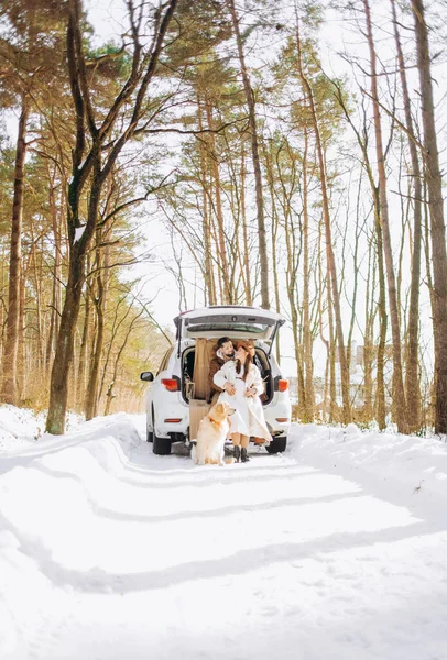 Bej renkli köpekli gülümseyen çift karlı ormanda açık bir arazi aracının bagajında oturuyor. Aktif kış tatillerinde birbirimizin keyfini çıkarıyoruz..