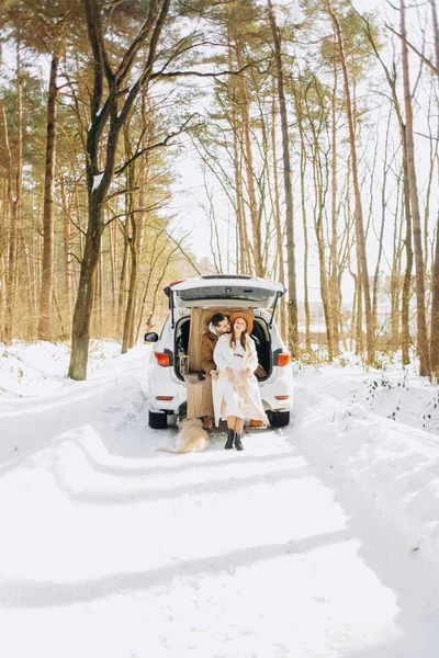Bej renkli köpekli gülümseyen çift karlı ormanda açık bir arazi aracının bagajında oturuyor. Aktif kış tatillerinde birbirimizin keyfini çıkarıyoruz..