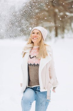 Mutlu sarışın kadın kış günü bir karla oynar. Kızlar kışı sever, dondurucu günü. Kış tatillerinde karla oynayan bir kadın, havaya beyaz kar fırlatır. Kış ormanlarında yürü.