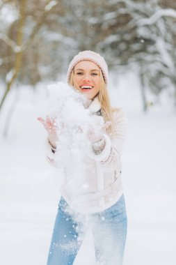 Kış Süeti Kuzu Ceketi içindeki güzel kız kış anlarının tadını çıkarıyor. Açık havada pembe şapkalı sarışının karlı bir sabahta bulanık bir arka planda eğlenirken çekilmiş fotoğrafı..