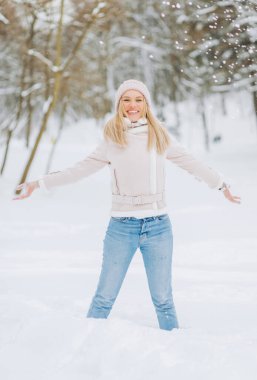 Kış Süeti Kuzu Ceketi içindeki güzel kız kış anlarının tadını çıkarıyor. Açık havada pembe şapkalı sarışının karlı bir sabahta bulanık bir arka planda eğlenirken çekilmiş fotoğrafı..