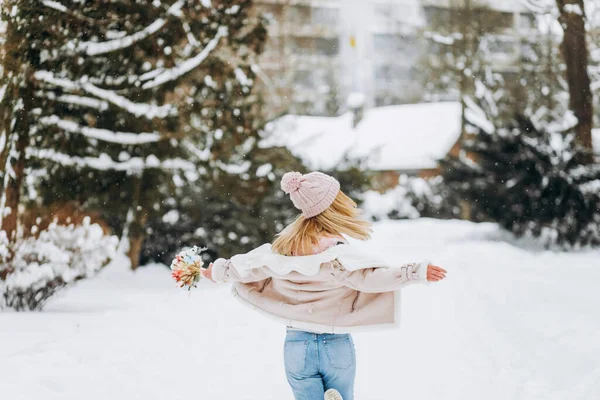 身穿冬衣的年轻女子提着一束精致的干花在公园里散步 — 图库照片
