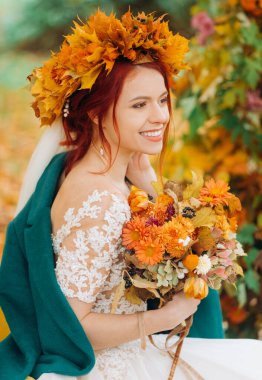 Gelinin parlak portresi, elinde bir buket sonbahar çiçeği ve kafasında sarı yapraklardan bir çelenk..