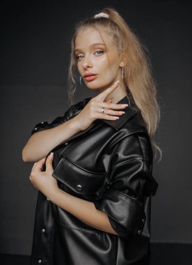 Siyah deri gömlekli, esmer, doğal makyajlı güzel bir sarışının portresi.