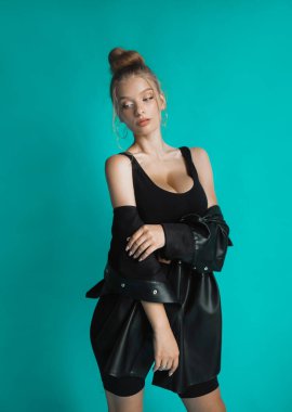 Turkuaz arka planda siyah bluzlu seksi sarışın.