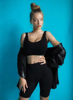 Siyah bluzlu ve turkuaz arka planda poz veren güzel bir kız.