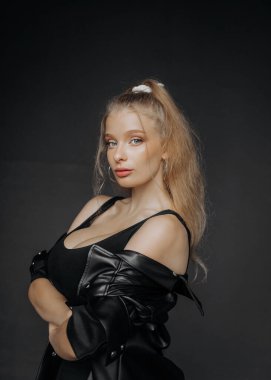 Siyah deri gömlekli, esmer, doğal makyajlı güzel bir sarışının portresi.