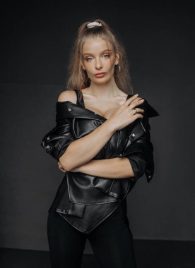 Siyah deri gömlekli, esmer, doğal makyajlı güzel bir sarışının portresi.