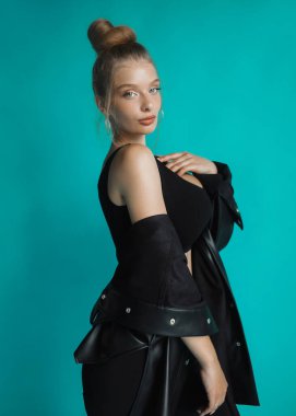 Siyah bluzlu ve turkuaz arka planda poz veren güzel bir kız.