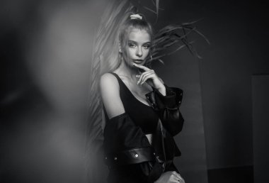 Gri bir arka planda poz veren şık saç stili olan şık bir kız.