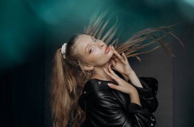 Gri arka planda seksi bir sarışının portresi. Arkaplanda turkuaz bulanıklık etkisi.