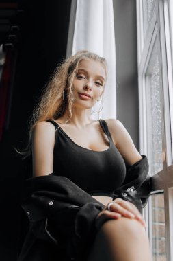 Pencerenin yanında şık siyah elbiseli şık bir sarışın..