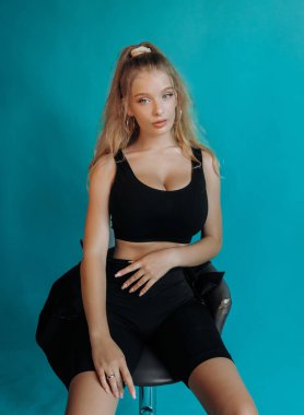 Stüdyoda bar taburesinde oturan tatlı sarışın. Turkuaz arkaplan.