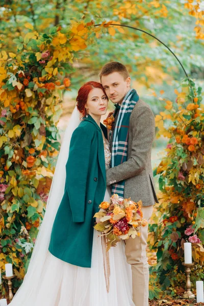 婚礼在秋天的公园举行 新婚夫妇站在装饰好的拱门旁边 — 图库照片