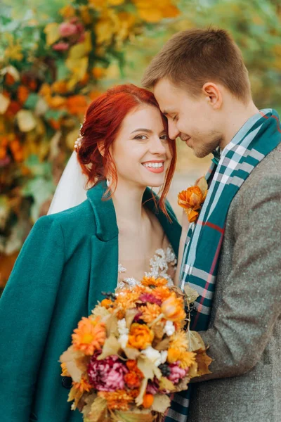 Düğün kemerinin yanındaki komik bir çiftin portresi. Kızıl kız ve yakışıklı adam birbirlerine sarılıyorlar..