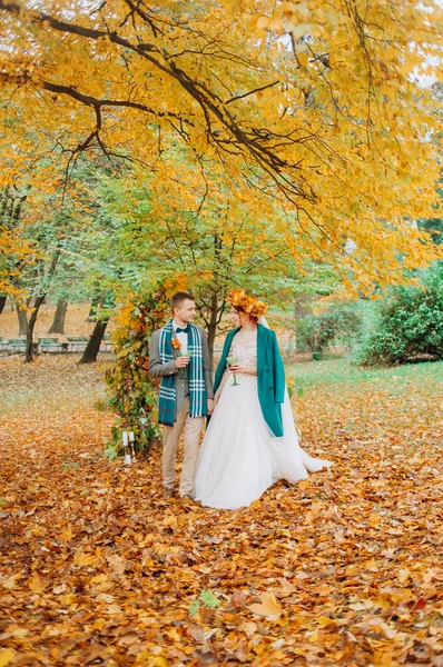 秋の公園を歩いている新婚旅行者は ワインを手に持っている — ストック写真