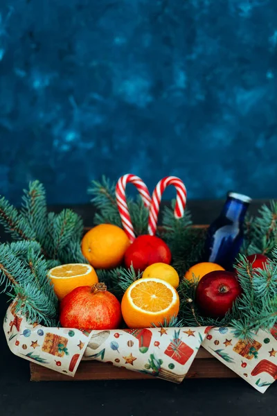 Taze meyve ve noel ağacı dallarıyla süslenmiş lolipoplarla dolu bir hediye kutusu. Noel Kompozisyonu