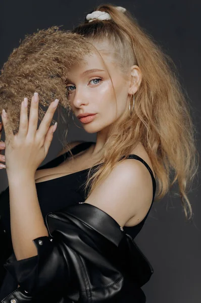 Stüdyoda kuru kamışlı sarışın bir kızın portresi. Yüzünü bir sazlığın arkasına gizliyor..