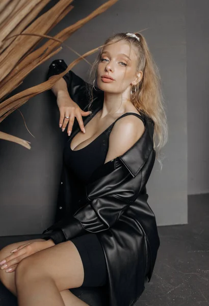 Fantastisk Blond Modell Klädd Svart Fashionabel Kostym Sitter Grå Bakgrund — Stockfoto