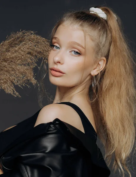 Stüdyoda kuru kamışlı güzel bir kızın portresi. Yüzünü bir sazlığın arkasına gizliyor..