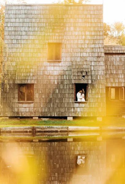 湖の近くの秋の公園で木製の気まぐれな居心地の良い家と愛のカップル — ストック写真