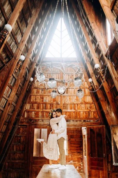 Genç çift, sıcak ahşap binanın içinde masanın üzerinde duruyor.