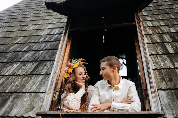 湖の真ん中にある木造の家の窓の近くに立つ若いカップル — ストック写真