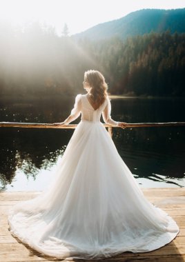 Gölün yanında lüks gelinlik içinde güzel bir gelin. Dağlarda düğün