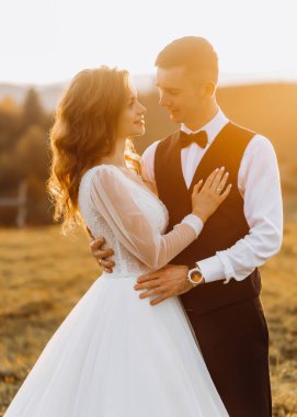 Güzel bir çift düğün günlerinde arka planda, dağlarda destansı bir günbatımında