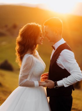 Güzel bir çift düğün günlerinde arka planda, dağlarda destansı bir günbatımında