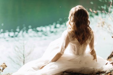 Genç gelin gölün kenarında oturuyor.